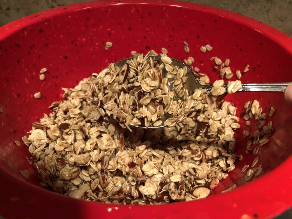 wet, unbaked granola on a spoon and in a red bowl